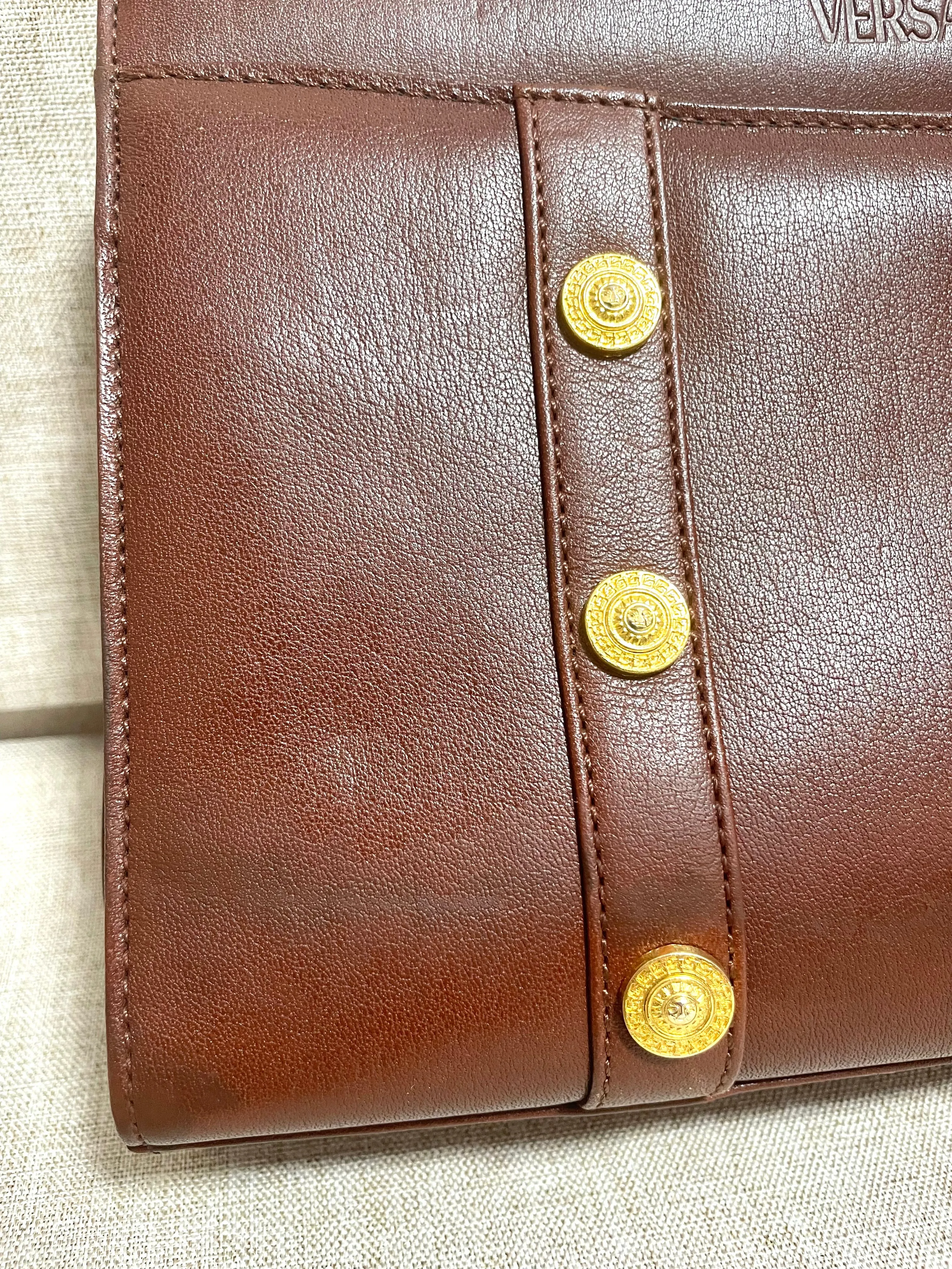 Vintage Gianni Versace brown leather wristlet, purse clutch, case bag with its iconic golden sunburst charms. Unisex bag. 061027y1